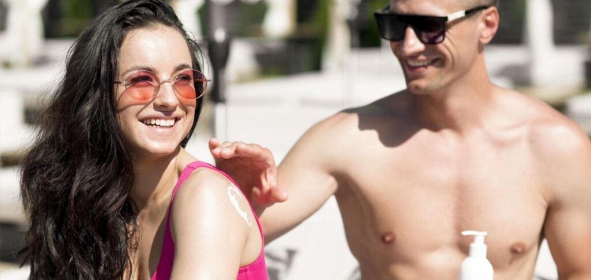 Young couple at the beach applying sunscreen on each other